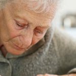 An elderly woman writes